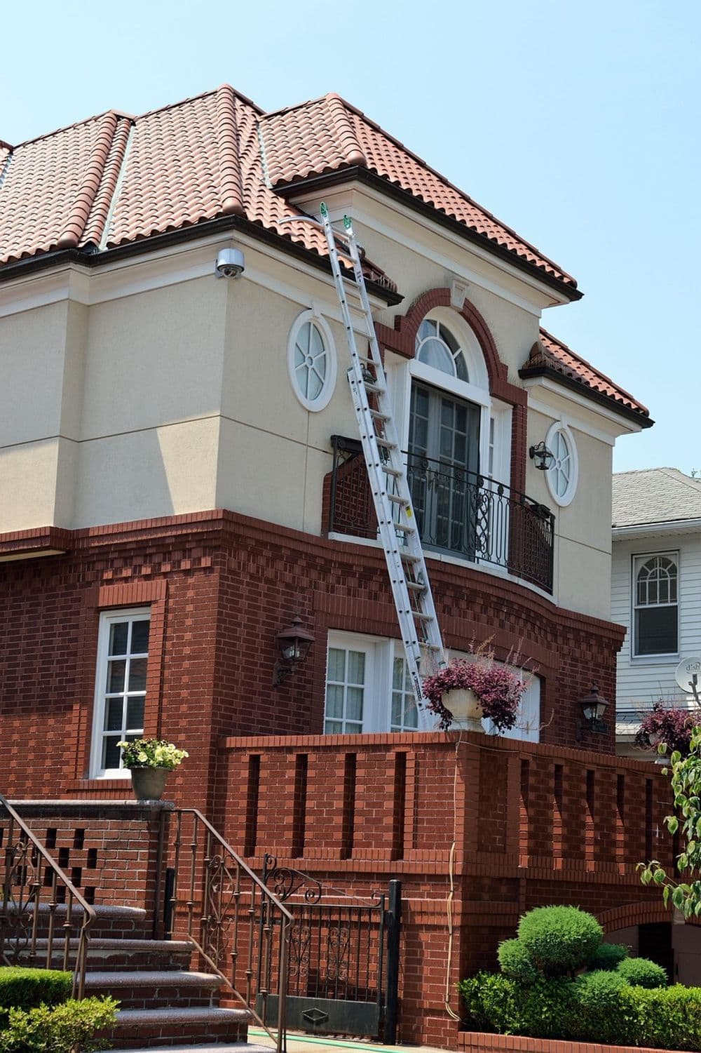 House with a red-brick facade, ladder leaning against the roof for maintenance work.