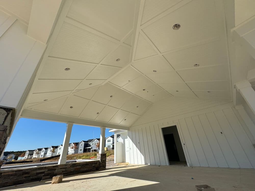 Spacious white-paneled porch with recessed lighting and modern architecture, new home construction.
