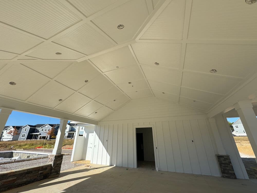 Modern outdoor patio with a vaulted white ceiling and recessed lighting, under construction.