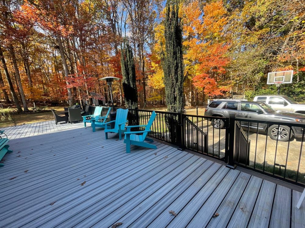 Scenic autumn backyard deck with turquoise chairs surrounded by colorful fall foliage.